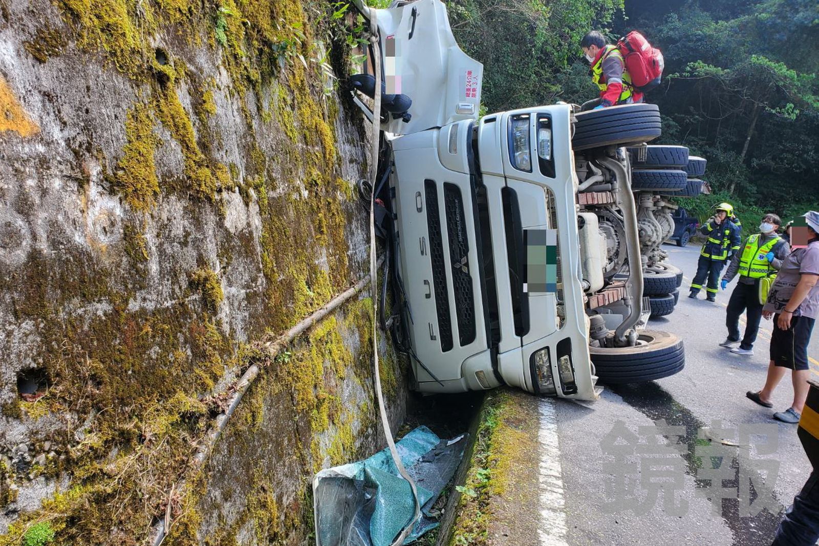 預拌混凝土車翻覆後擦撞山壁，駕駛一度受困車內，消防隊員到場搶救。民眾提供