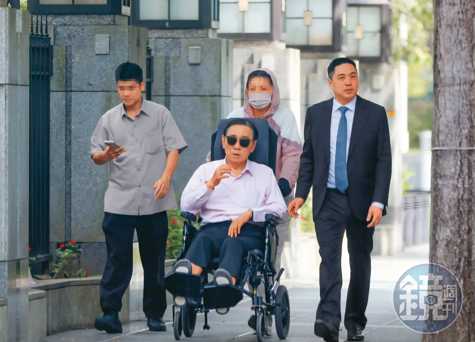 王文洋(左2)本月14日坐輪椅出門,兒子王泉仁(右1)、幫傭以及保鑣都跟在他身旁。圖/翻攝《鏡週刊》