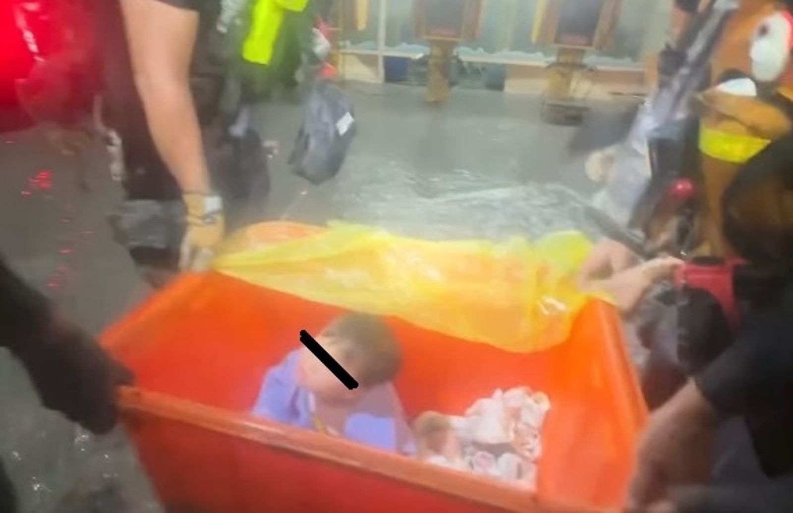 救難人員把受災幼童裝進大型橘色水桶,將他們從湍急的水流中脫困。圖/翻攝自LINE群組