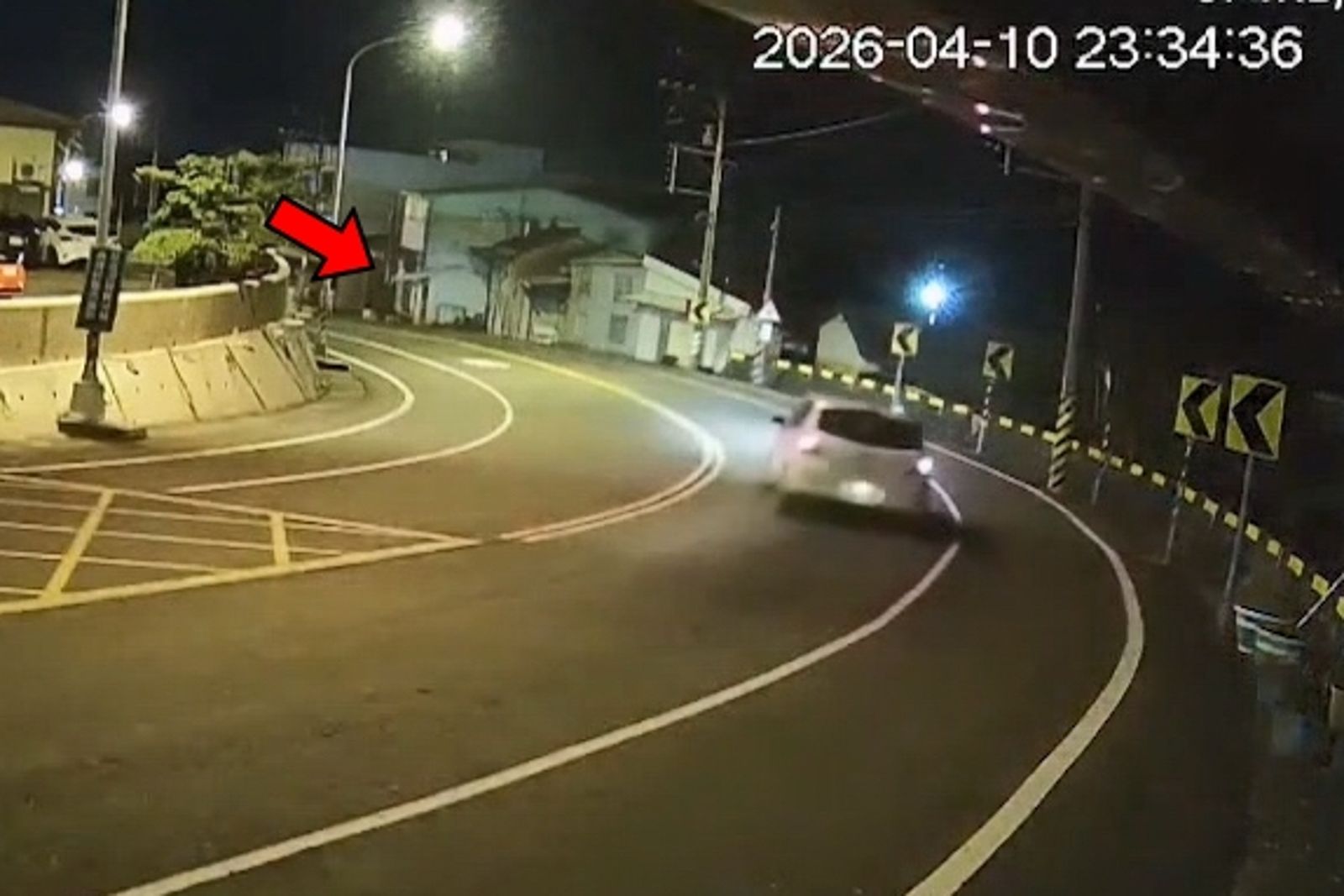 白色轎車過彎失控,撞上路旁的電線桿與民宅(箭指處)。民眾提供