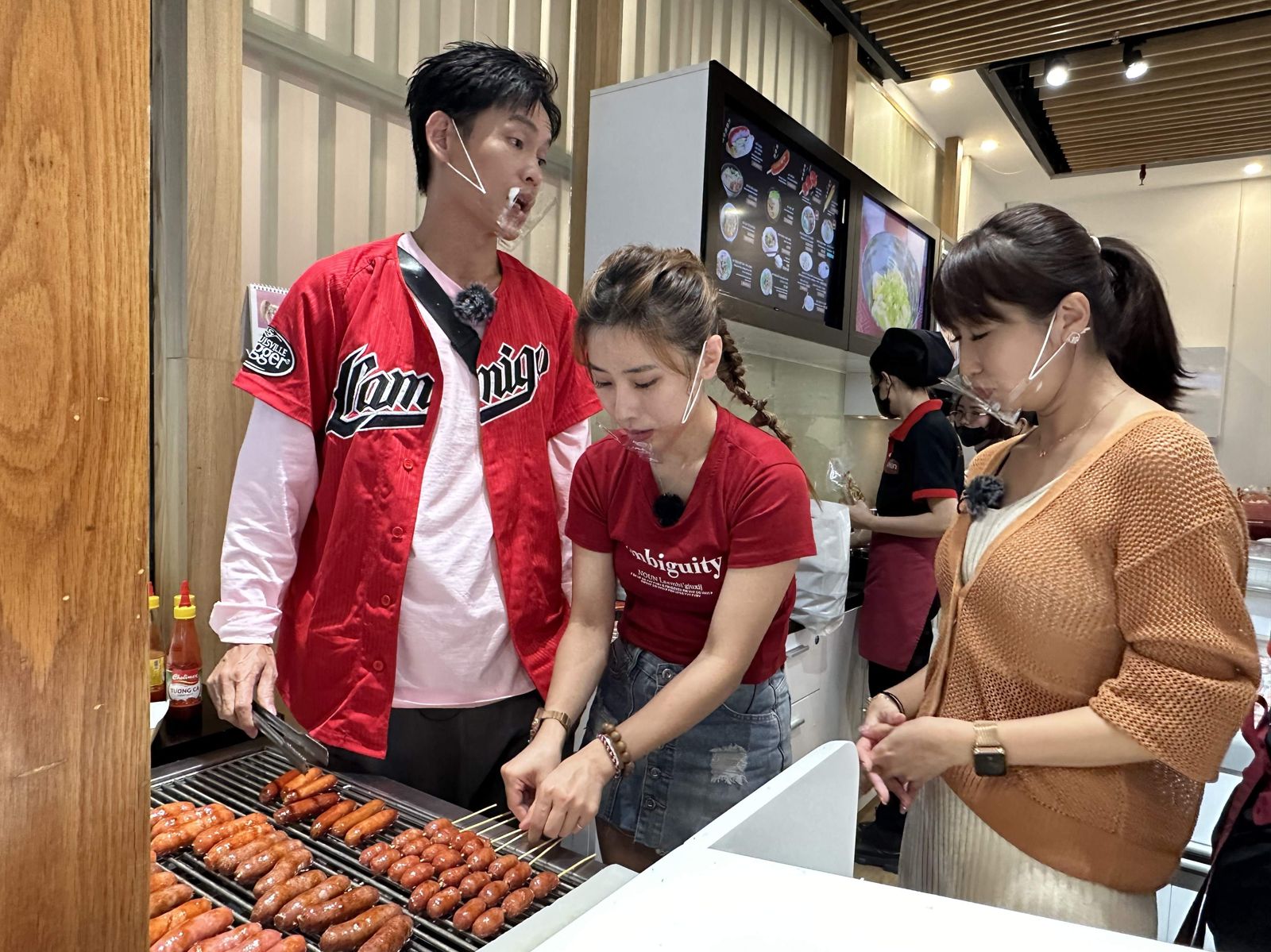 （左起）黃鐙輝與陳怡婷一起煎香腸並詢問Elly如何才能美味。公視台語台提供