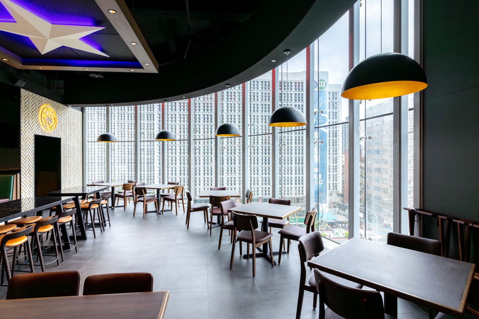 「Roadhouse德州鮮切牛排」大巨蛋店以大片落地窗引入城市光景，深色調搭配俐落線條，打造時髦都會風用餐空間。（圖／開展餐飲集團）