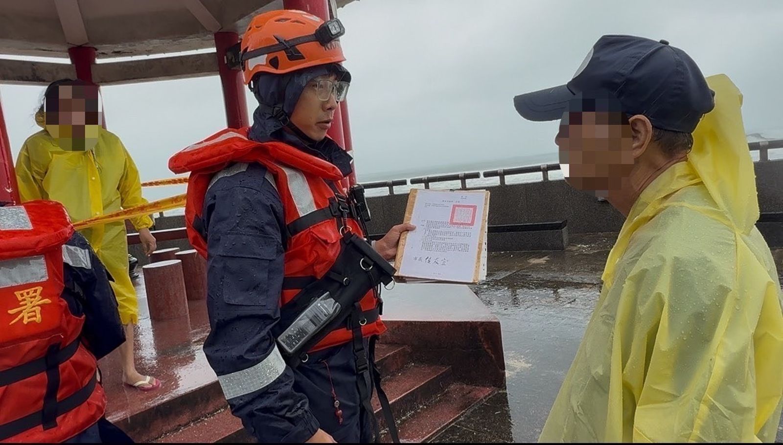 2民眾昨(11日)於新北萬里龜吼漁港涼亭觀浪,海巡人員為考量安全將人帶回。翻攝畫面