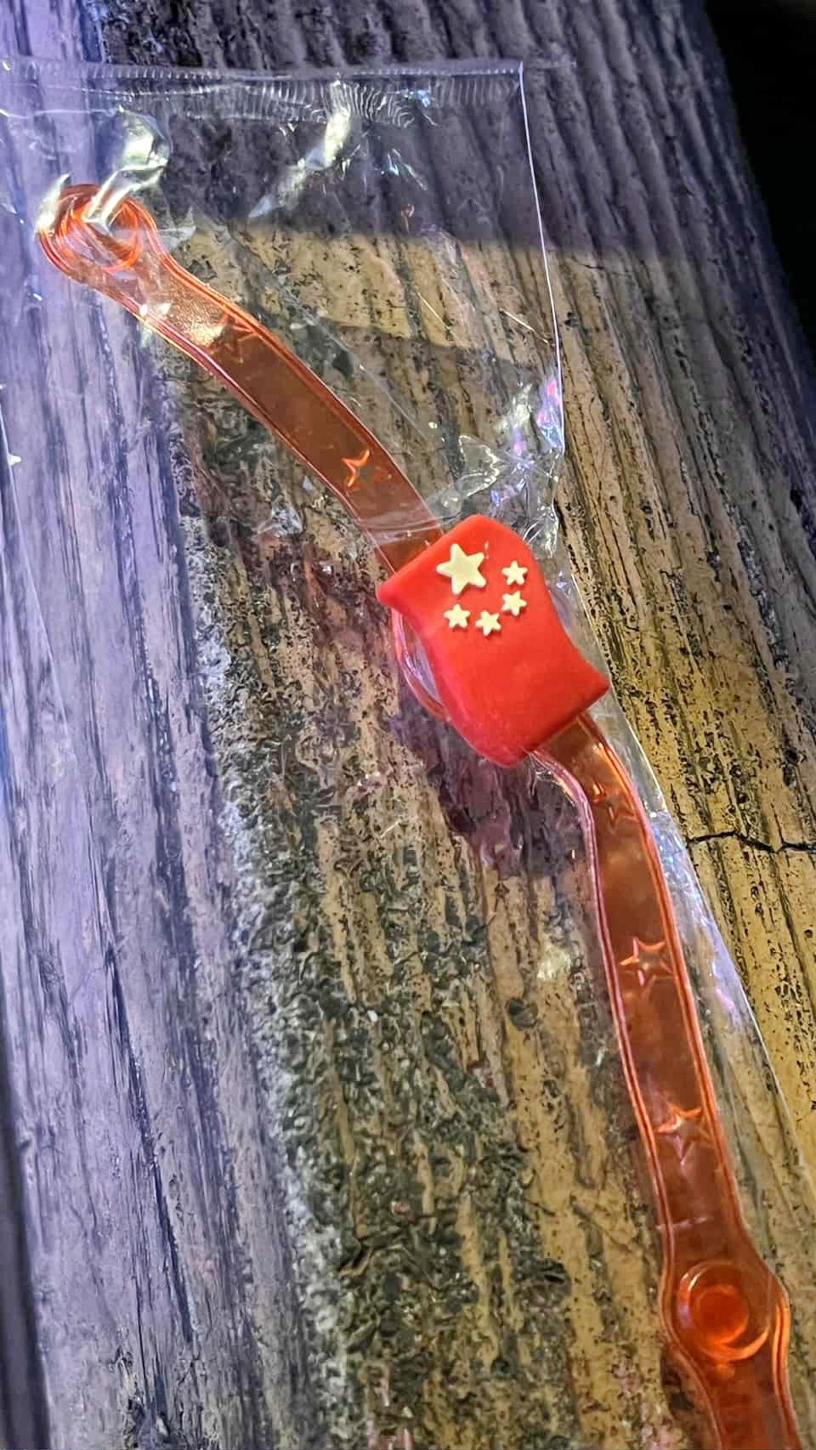 北港藝閣花車發送類似錶帶的中國五星旗小物，小孩撿到馬上丟掉，家長也質疑「北港藝閣為什麼要發中國國旗？」。畫面翻攝threads aki_lim_tw