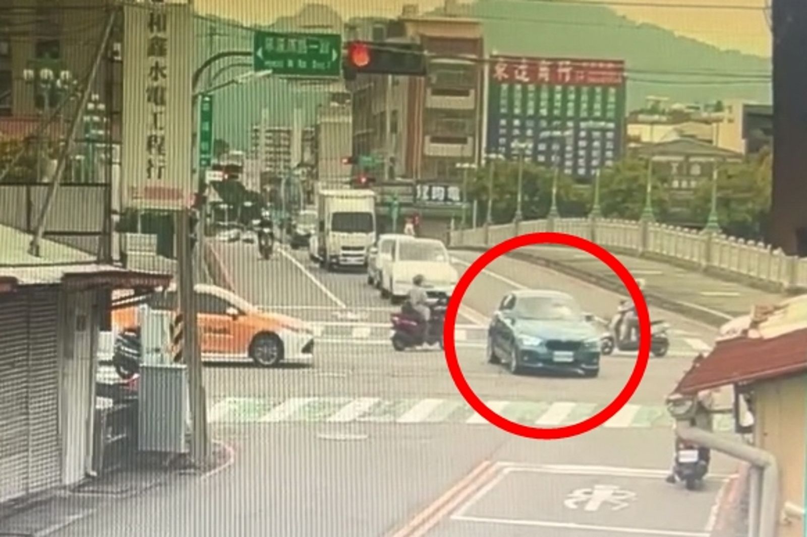 李姓男子(紅圈處)酒駕開著藍色轎車,在路口緩慢滑動前進,無視路口已經是紅燈,許多駕駛見狀小心閃避。圖/民眾提供