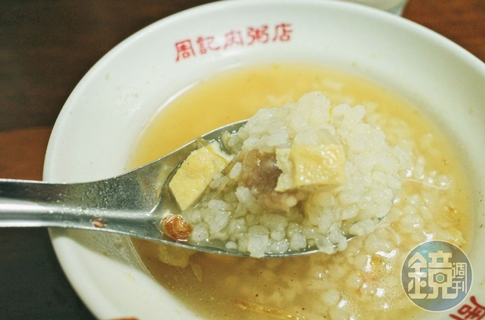 周記的肉粥不同於一般稀飯或軟綿的廣東粥，店家以生米熬煮，保持米粒分明宛如高湯泡飯的口感。湯頭是用大骨熬製，並加入油豆腐碎、碎肉焿、油蔥酥和蝦米提味。圖／鏡週刊提供