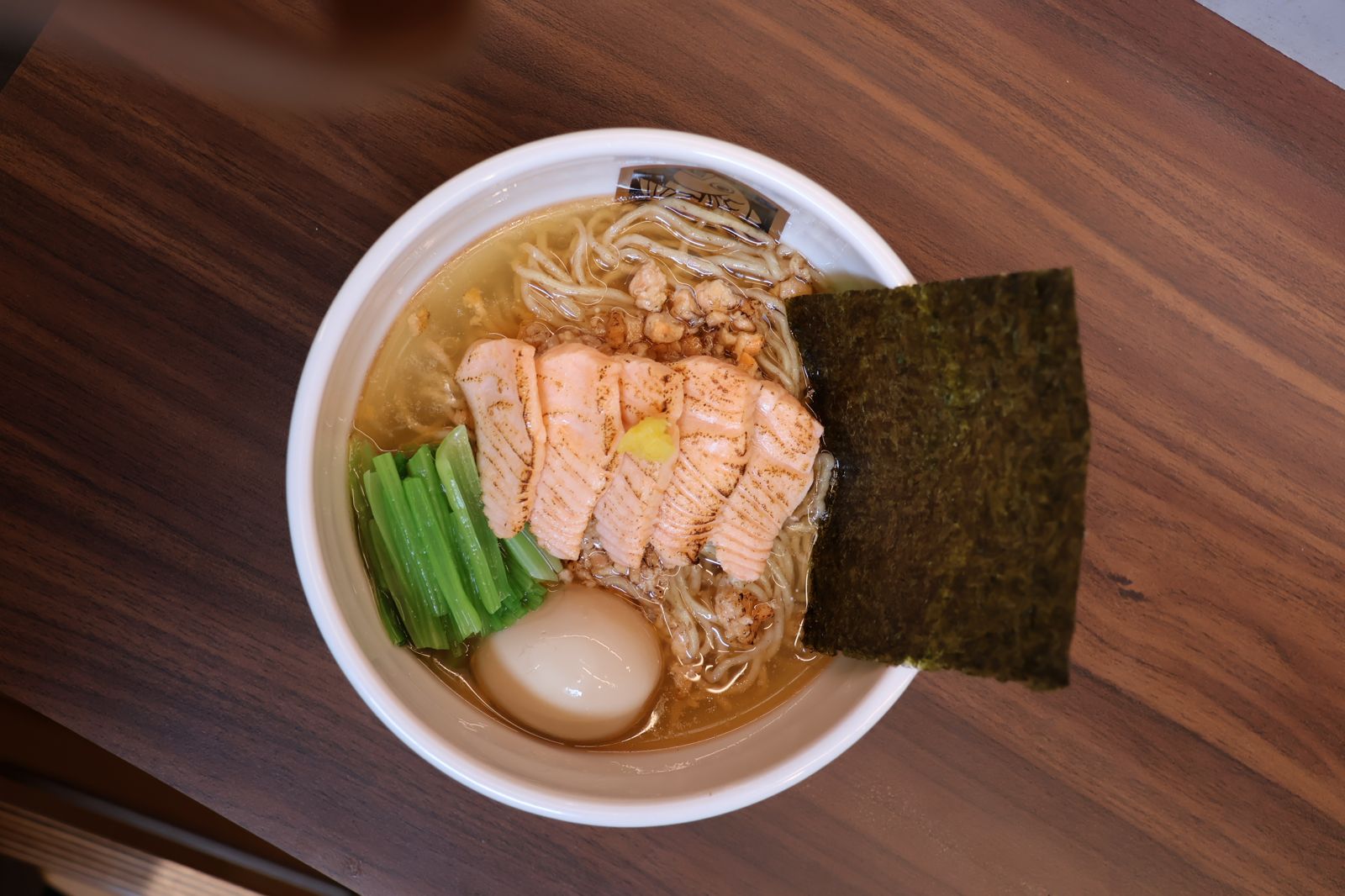 「特製鮮鮭魚湯拉麵」以鮭魚骨慢火熬製湯頭，搭配鮭魚魚鬆、炙燒生食級鮭魚與小松菜，鮮魚香氣層層堆疊。（398元／碗，圖／麵魚）