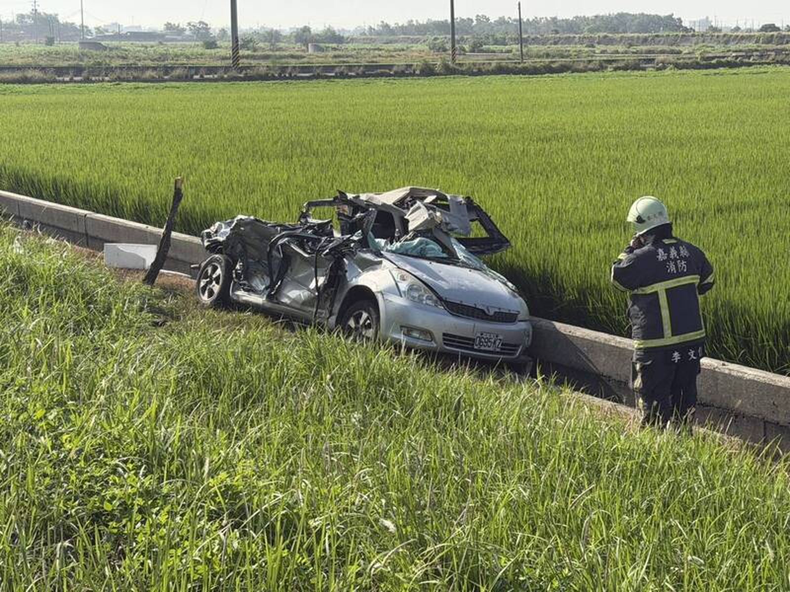 轎車嚴重扭曲變形，卡在田邊溝渠內。讀者提供