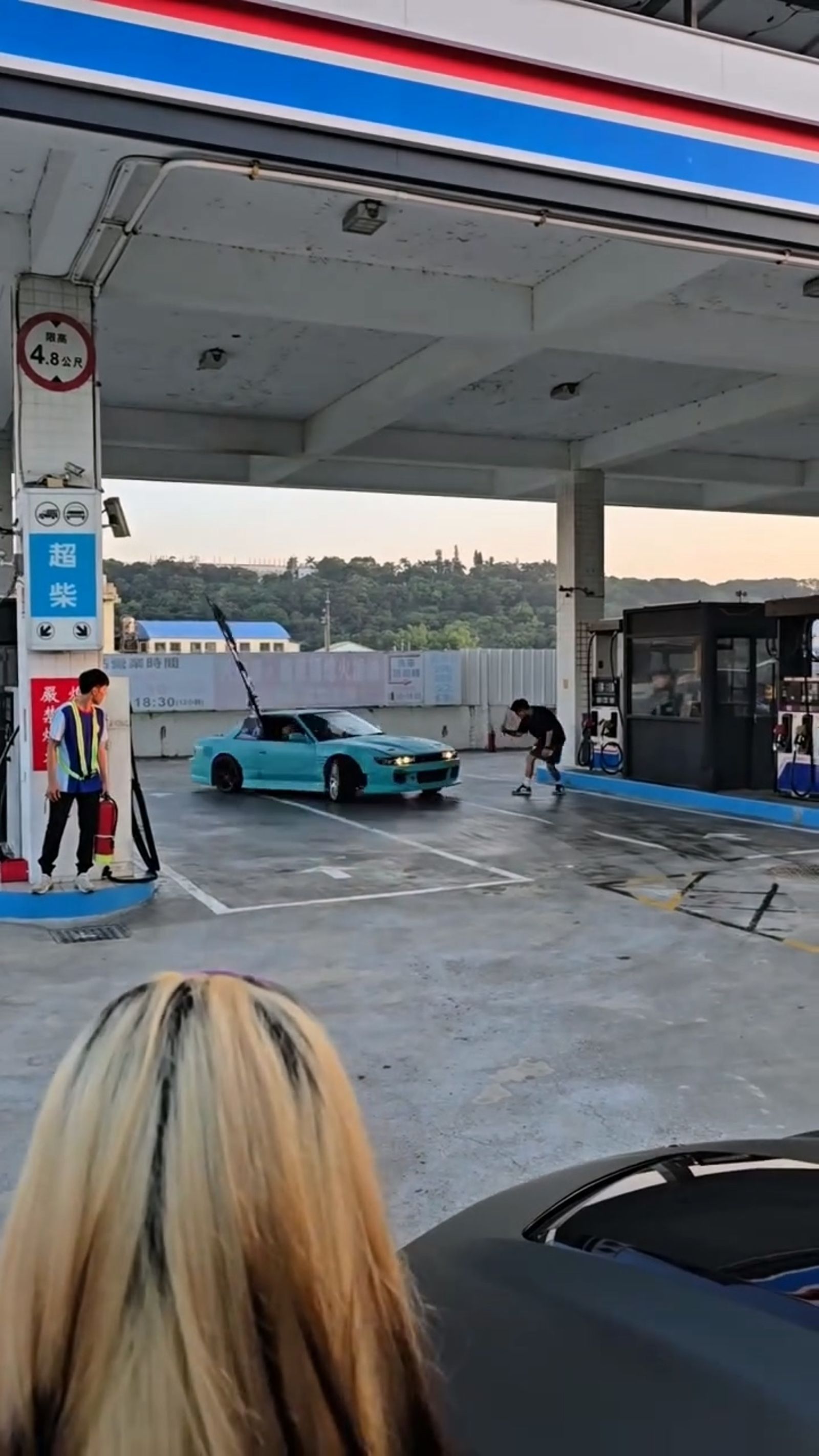 藍色改裝車在加油站內飄移甩尾,旁邊有工作人員持滅火器戒備,好幾位民眾拿著手機拍攝畫面。翻攝fb藍董