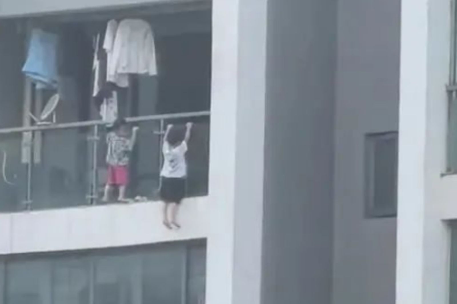 中國2男童13樓玩起「引體向上」，手抓玻璃雙腳騰空畫面曝光。圖／翻攝自微博