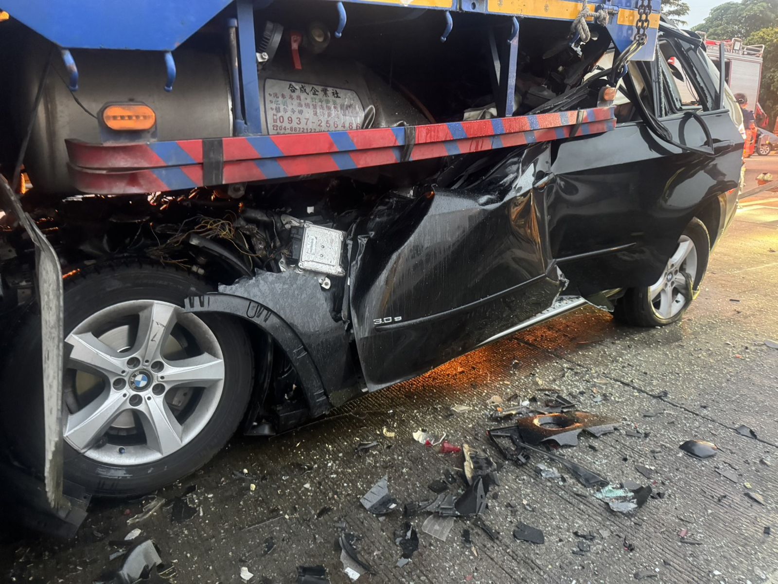 黑色BMW休旅車車頭卡在大貨車後車斗下方。讀者提供