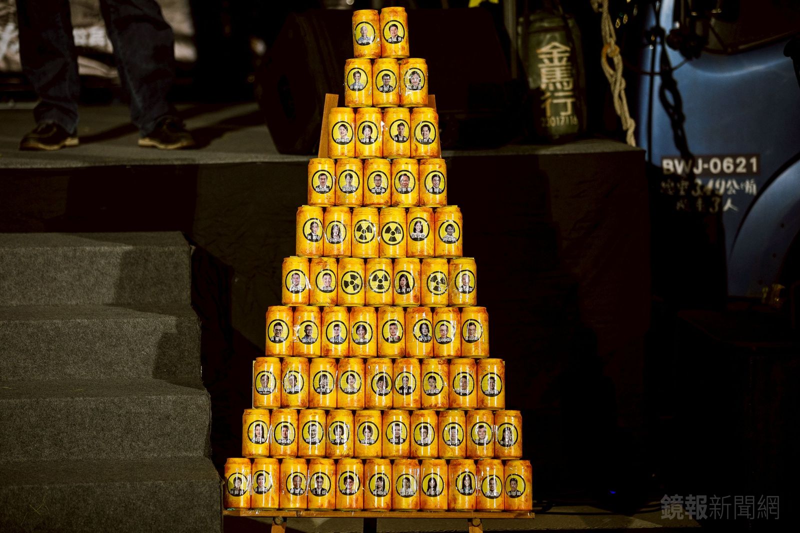 反核團體在舞台前架起罐頭塔，象徵核廢料，罐頭上面貼著藍白立委大頭照。（圖／鄒保祥攝）