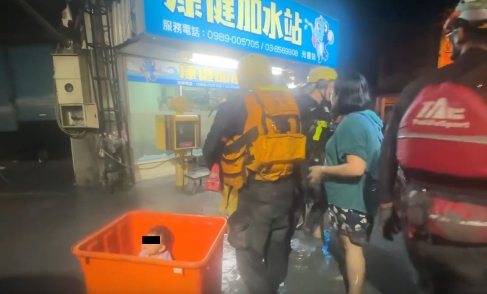 救難人員把受災幼童裝進大型橘色水桶,將他們從湍急的水流中脫困。圖/翻攝自LINE群組