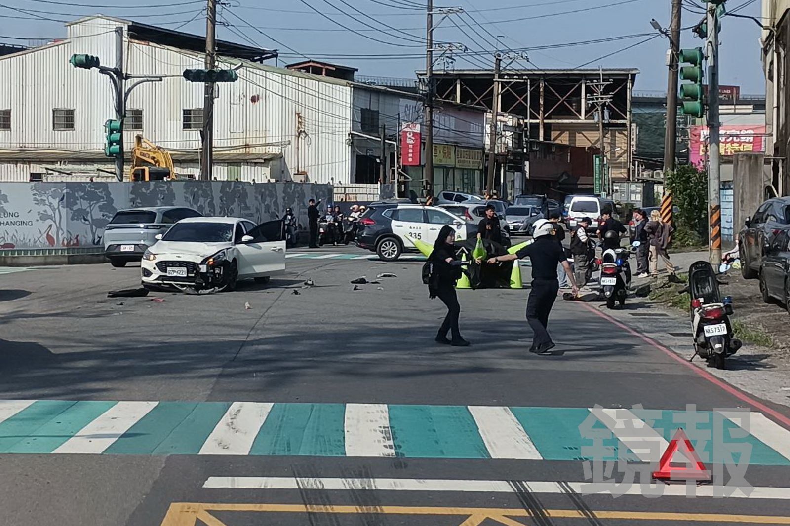 白色轎車與機車發生碰撞，造成騎士當場死亡，現場滿地碎片油漬，警方架設帳篷覆蓋遺體、管制車禍現場，由鑑識小組進行調查採證。民眾提供