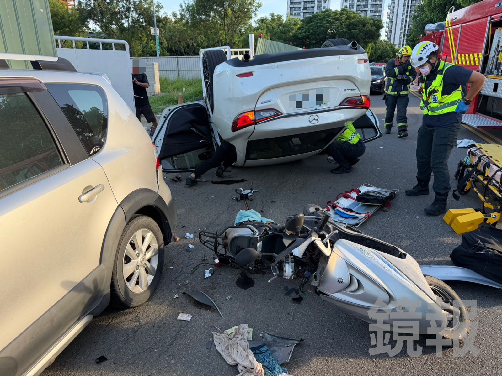 白色轎車翻覆,1名乘客受困車內,機車騎士被壓在車底,消防隊員展開搶救。民眾提供