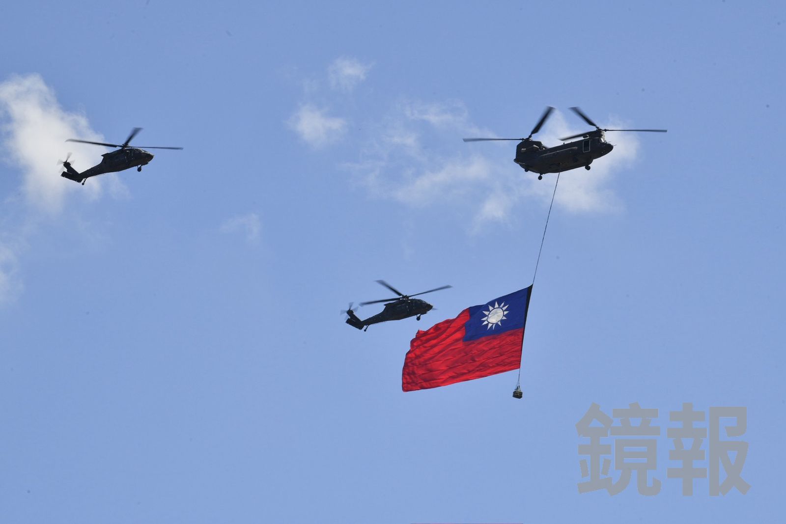 國歌響起時,陸軍UH-60M黑鷹直升機與CH-47SD契努克運兵直升機吊掛國旗,飛越總統府前方廣場上空。(圖/李智為攝)