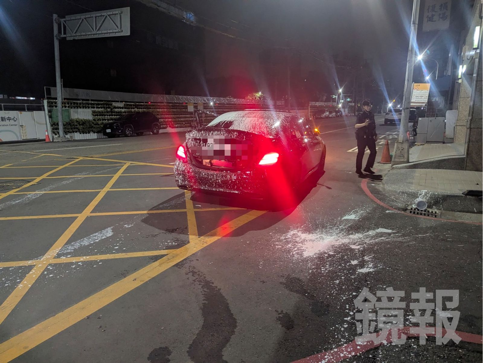 黑色轎車遭潑灑大量白色油漆,路面留下不少油漆殘漬。民眾提供