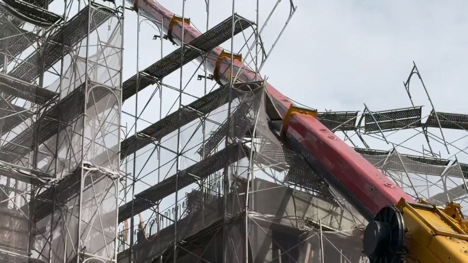 吊車往建案工地方向傾斜,吊臂擊中建築物的鷹架結構。民眾提供