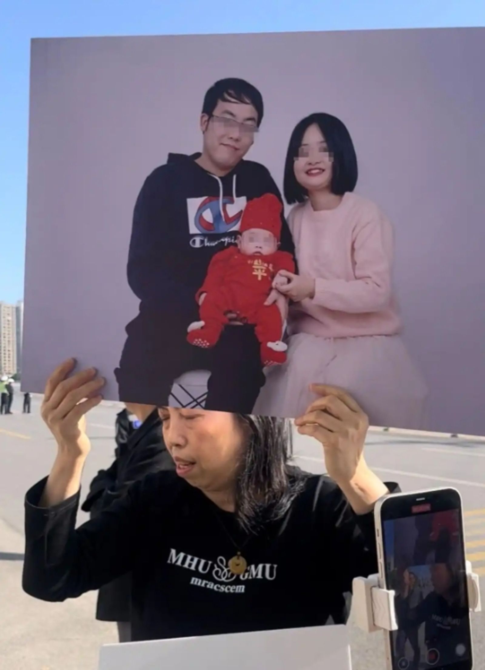 胡女拿著兒子一家三口的照片在法院外要求判處肇事者死刑。圖／百度