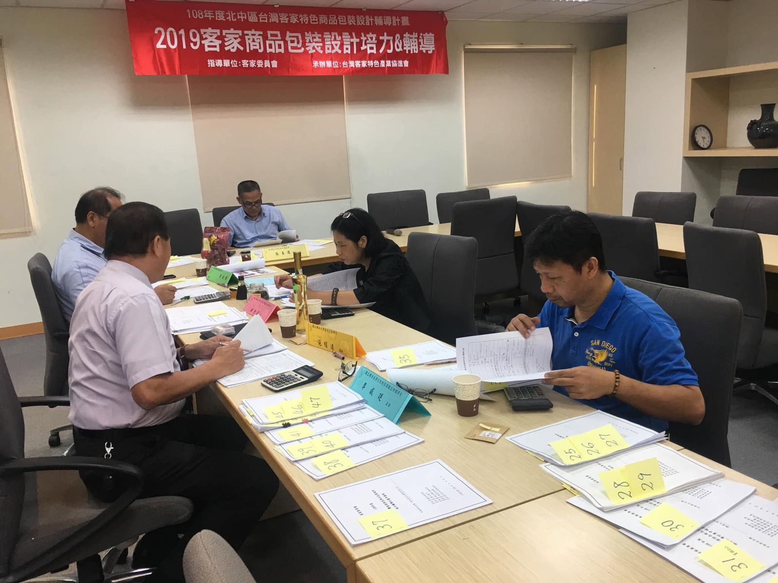 聯大文創系系主任李威霆(藍衣者)評選客家特色產業包裝設計商品。圖／翻攝fb文化創意與數位行銷學系