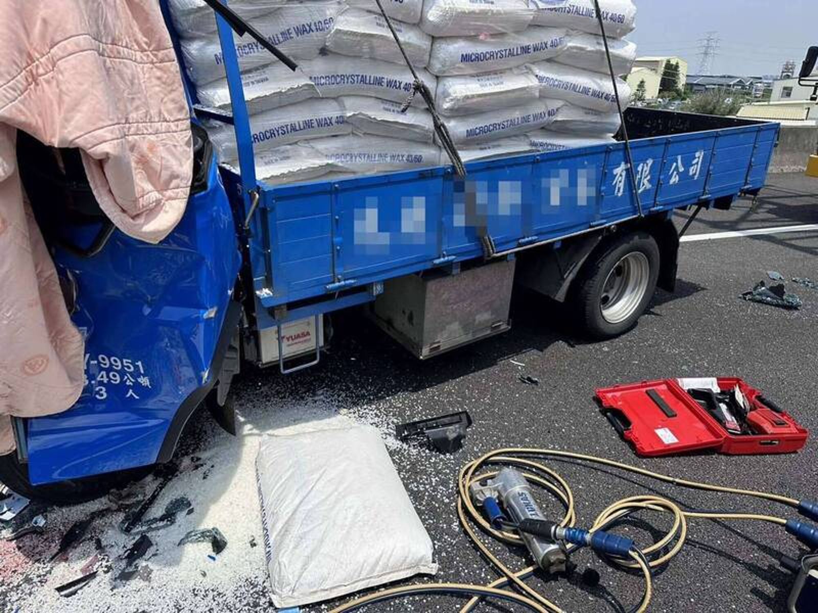 小貨車車頭變形，載運的白蠟顆粒散落一地。民眾提供