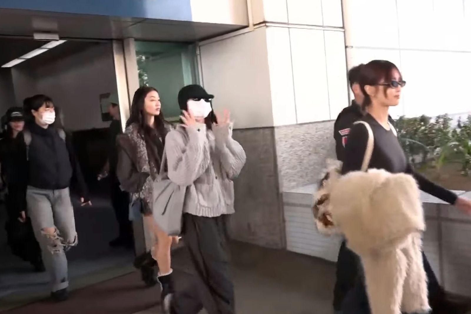 穿著灰色針織外套戴著帽子與口罩的娜璉,對鏡頭揮手。翻攝《鏡新聞》