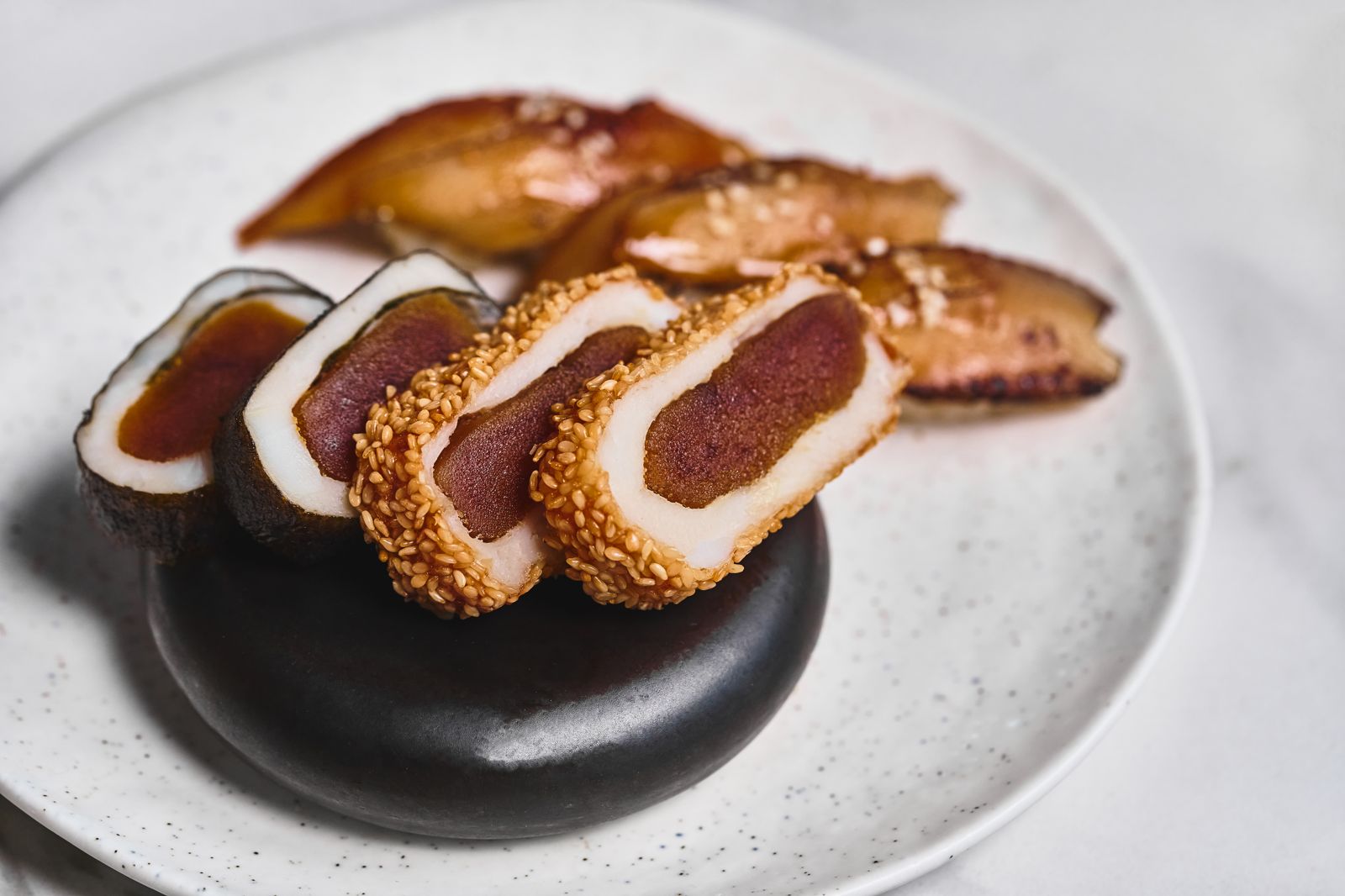 「雪花烏金唐千壽」以花枝漿包覆烏魚子，外裹白芝麻與海苔酥炸，巧妙平衡傳統與創新。（饗賓集團供圖）