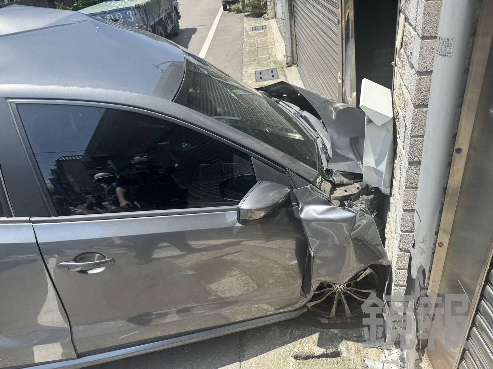 轎車遭推撞,造成民宅鐵捲門也被波及受損。民眾提供